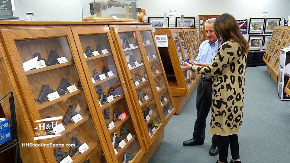 Leroy Ussery, Owner of H&H Shooting Sports, shows a handgun to a buyer in front of the pistol display caser.